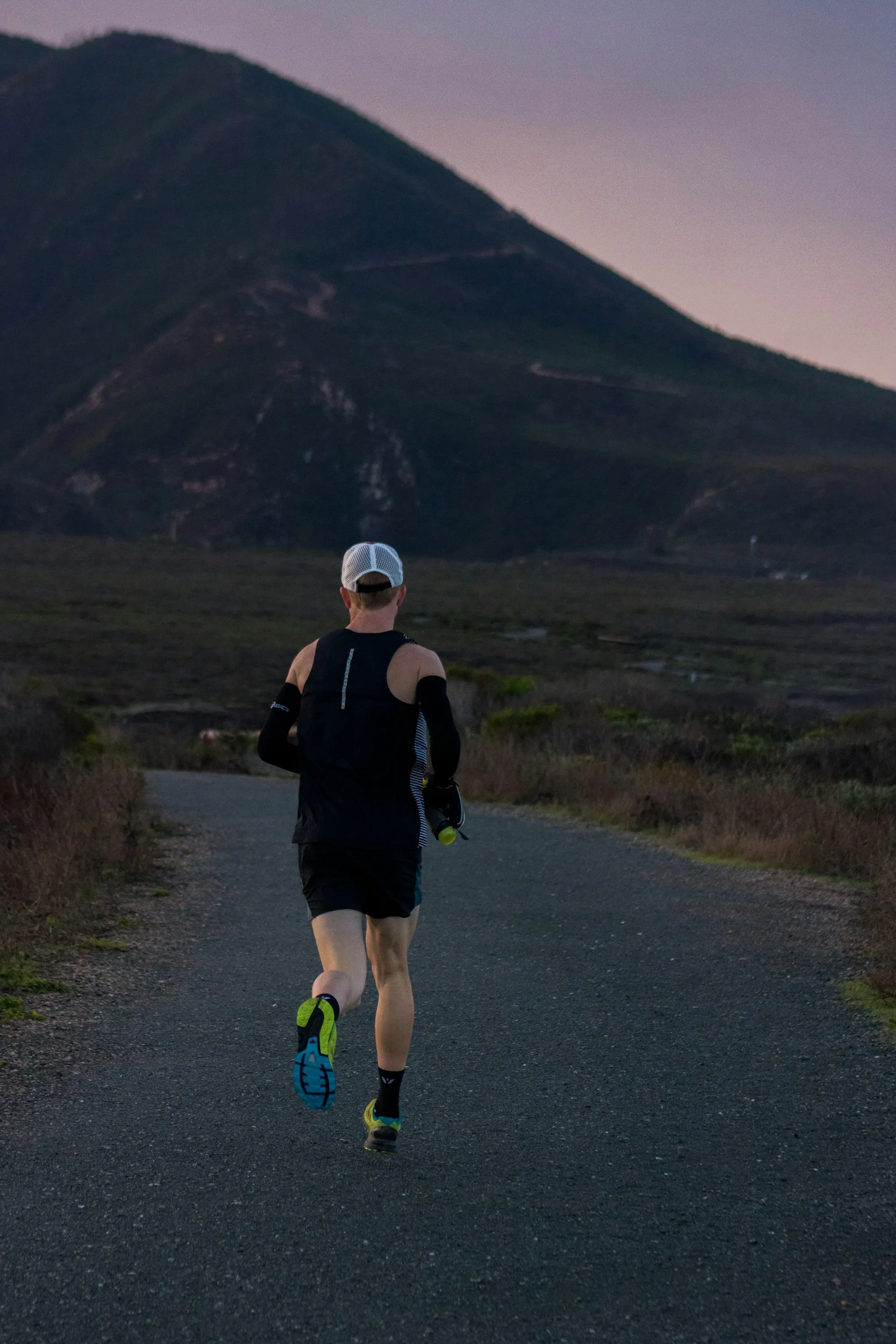 A woman jogging on a road across the mountains